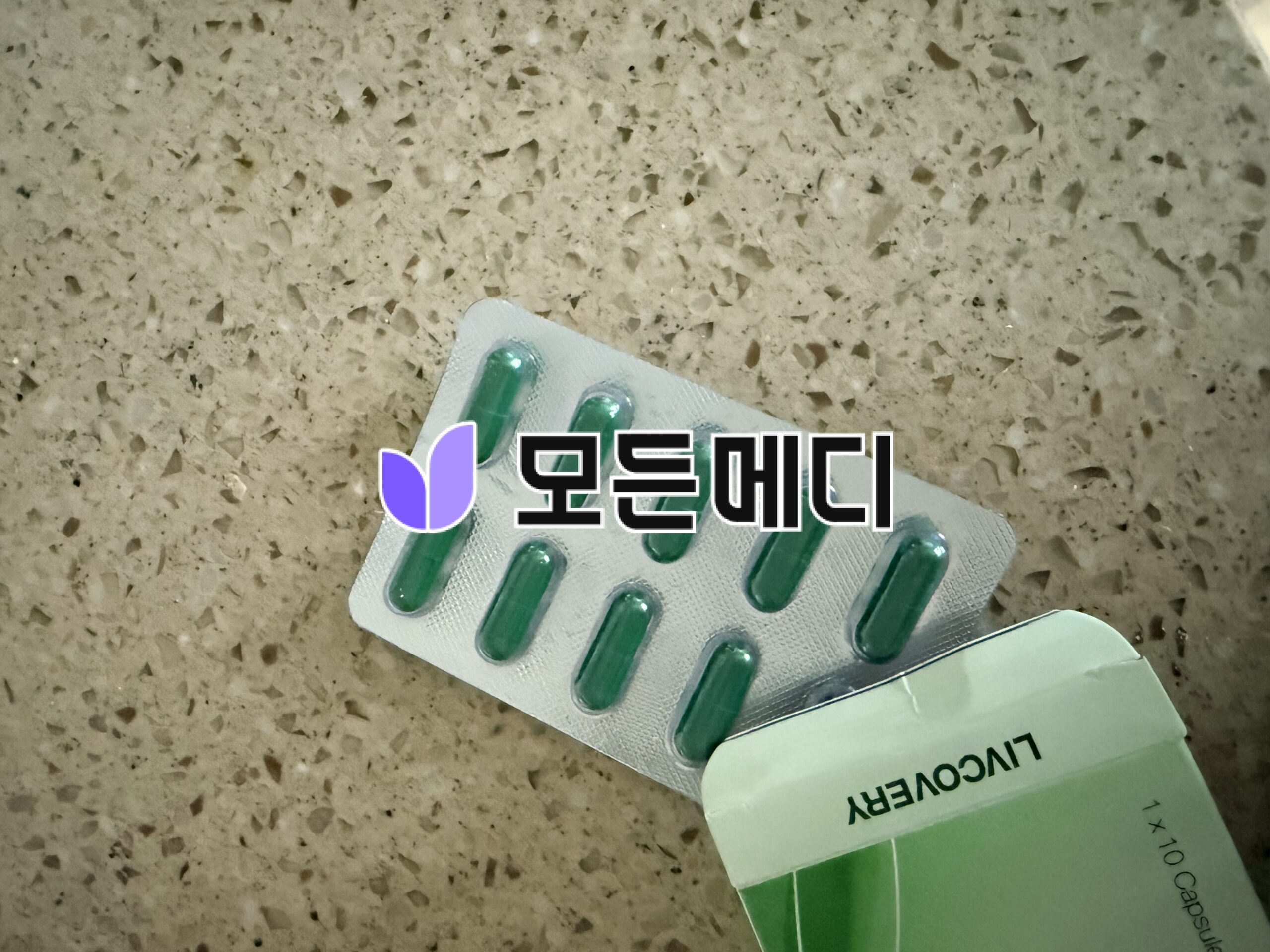 Blister pack with green soft gel capsules on a speckled beige countertop.